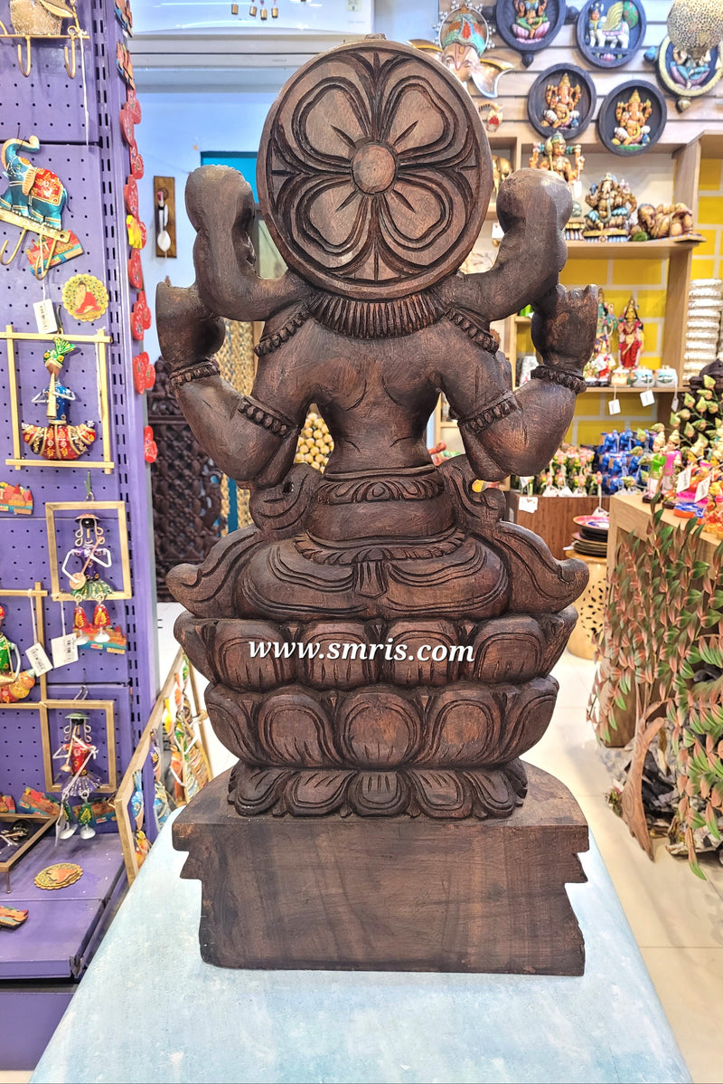 Wooden statue of a deity with intricate carvings in a store setting.